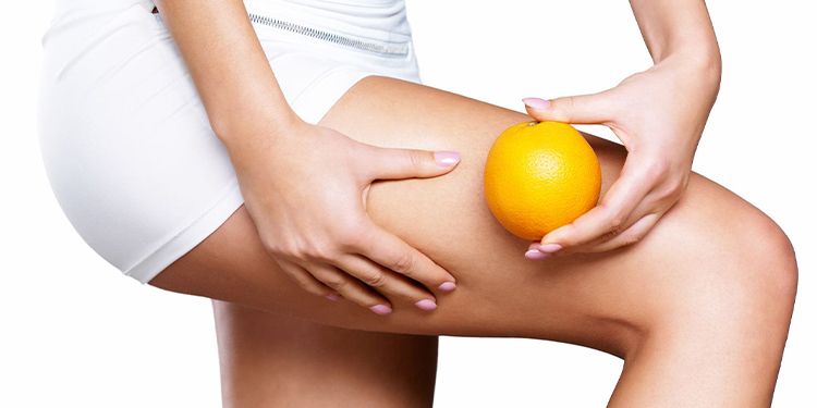 Elinde portakal tutan ve selülitsiz bacaklarını gösteren genç kadın